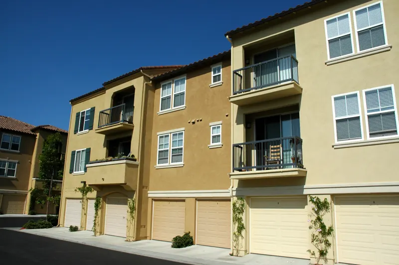 Three-storey stucco condominium building in Southern California with garages tucked under the units
